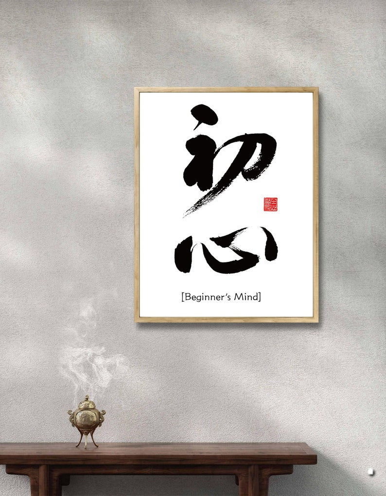 Pu&ograve; includere: Una stampa incorniciata con un design di calligrafia in bianco e nero dei caratteri giapponesi per "Beginner's Mind" in una cornice nera semplice su sfondo bianco. Il testo "[Beginner's Mind]" &egrave; stampato sotto la calligrafia.