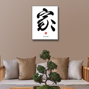 May include: A black and white calligraphy print of the Japanese character for "home" on a white background. The character is written in a bold, brushstroke style. The word "Home" is written in English below the character in black.