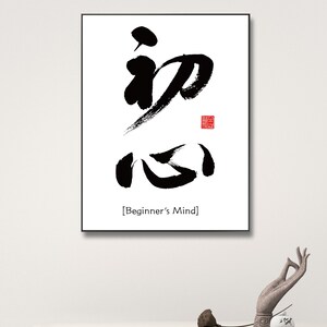 Pu&ograve; includere: Stampa d'arte calligrafica in bianco e nero con i caratteri giapponesi per "Mente del principiante" in una cornice nera. La stampa &egrave; su sfondo bianco e ha un sigillo rosso nell'angolo in alto a destra.