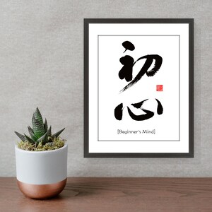Pu&ograve; includere: Stampa d'arte calligrafica in bianco e nero in una cornice nera con la parola giapponese "初心" (Shoshin) che significa "Mente del principiante".