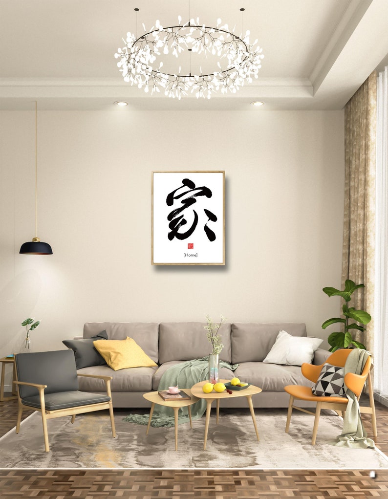 May include: A framed calligraphy artwork featuring the Chinese character for "home" in black ink on a white background. The character is written in a bold, brushstroke style. The frame is gold and the artwork is hanging on a white wall in a living room setting.