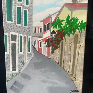 Puede incluir: Una pintura de una calle estrecha en un pueblo europeo. Los edificios est&aacute;n pintados en tonos de gris, rojo y amarillo. Hay plantas verdes y flores rojas creciendo a lo largo del lado de la calle. La pintura est&aacute; firmada "2022 Suzanna Teodossievic".