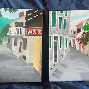 Puede incluir: Dos pinturas que representan calles estrechas y sinuosas en un pueblo europeo. La primera pintura muestra una panader&iacute;a con un letrero que dice "PEKARA". La segunda pintura muestra una calle con un muro de piedra y un edificio rojo. Ambas pinturas est&aacute;n firmadas por la artista, "Suzana Todosevic", y fechadas en "2022".