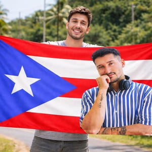 May include: Two people holding a Puerto Rican flag, featuring a white star on a blue triangle, with red and white stripes. One person wears a striped shirt and headphones. The background includes trees and a road.