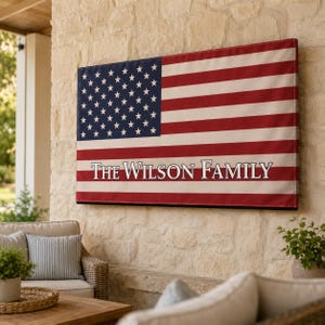 Op de afbeelding: Een rechthoekige wandhanger met het ontwerp van de vlag van de Verenigde Staten, voorzien van rode en witte horizontale strepen en een blauw kanton met witte sterren. De tekst "The Wilson Family" staat in witte hoofdletters in het midden.