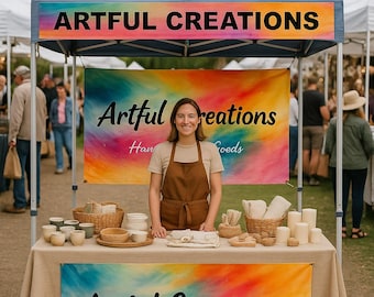 May include: A vendor booth with a light blue canopy and colorful banners reading "Artful Creations Handcrafted Goods." The booth displays handcrafted pottery, candles, and other goods. The vendor is wearing a brown apron.