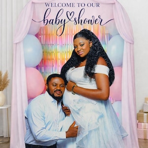 Puede incluir: Un tel&oacute;n de fondo para baby shower con el texto "WELCOME TO OUR baby shower" en una escritura elegante. El tel&oacute;n de fondo presenta a una persona embarazada con un vestido blanco y a una persona con una camisa azul. Se ven globos rosas y azules.