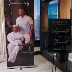 May include: A black and white wedding sign with the text "WELCOME TO THE WEDDING OF Angeanette AND Bernard FEBRUARY 14 2024" in a cursive font.