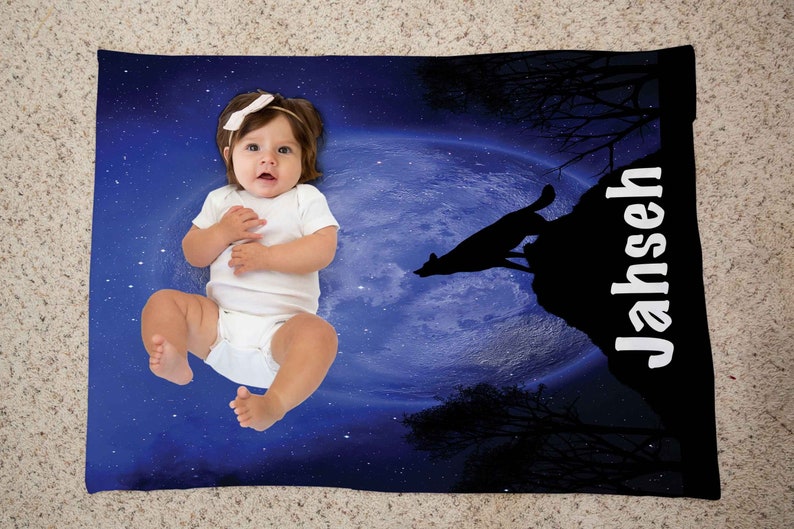 Puede incluir: Una manta para beb&eacute; azul y negra con un lobo blanco aullando a la luna. La manta tiene un fondo de cielo nocturno estrellado y el nombre "Jahseh" impreso en blanco en el lado derecho.