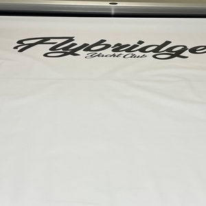 Pu&ograve; includere: Uno striscione bianco con il testo "Flybridge Yacht Club" stampato in nero.