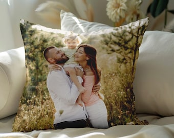 May include: A throw pillow with a photo of a family of three in a field. The parents are holding their child, who is smiling. The photo is in a warm, natural color palette.