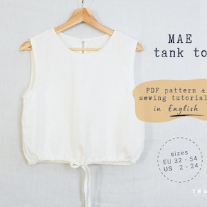 Könnte beinhalten: Ein weißes Tanktop hängt an einem Holzbügel. Das Oberteil hat einen Kordelzug in der Taille und ist ärmellos. Der Text auf dem Bild lautet "MAE tank top" und "PDF pattern & sewing tutorial in English". Größen EU 32-54, US 2-24.