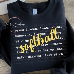 May include: Black sweatshirt with the word "softball" in yellow letters. The word is surrounded by a repeating pattern of the words "Limitless Creations by Kim & Kate" and various softball terms.