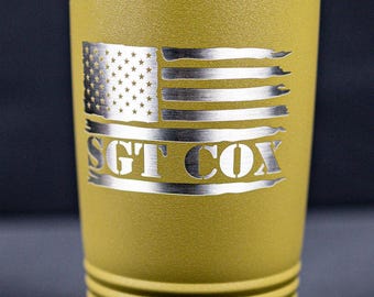 May include: A green stainless steel tumbler with a silver lid. The tumbler has a distressed American flag design and the text "SGT COX" engraved on the front.