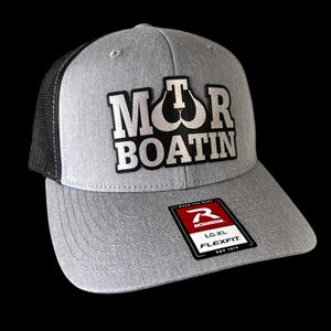 May include: A gray trucker hat with a black mesh back and a curved brim. The hat features the text "MTR BOATIN" in a white, stylized font. A red and white tag with the Richardson logo is attached.
