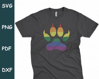Puede incluir: Una camiseta gris oscuro con un diseño de huella de pata arcoíris. La huella de pata es al estilo de una pata de oso.
