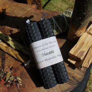 May include: Two black beeswax candles with a label that reads "Empress of the Moon" 100% Beeswax Candles Hecate Protection - Neutralise Negativity"
