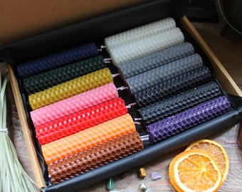 May include: A set of 12 honeycomb beeswax candles in a variety of colors, including red, orange, yellow, green, blue, purple, and black. The candles are arranged in a wooden box with a black lining.