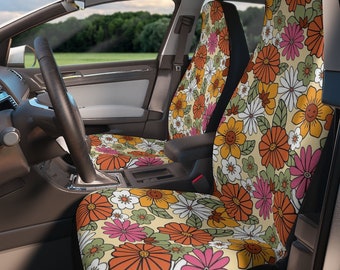 Puede incluir: Un par de fundas para asientos de coche con un patrón floral retro con flores naranjas, rosas, blancas y verdes sobre un fondo crema.