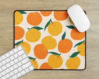 May include: A rectangular mousepad with a repeating pattern of orange and yellow oranges with green leaves on a cream background. A white computer mouse and a keyboard are on the wooden surface.