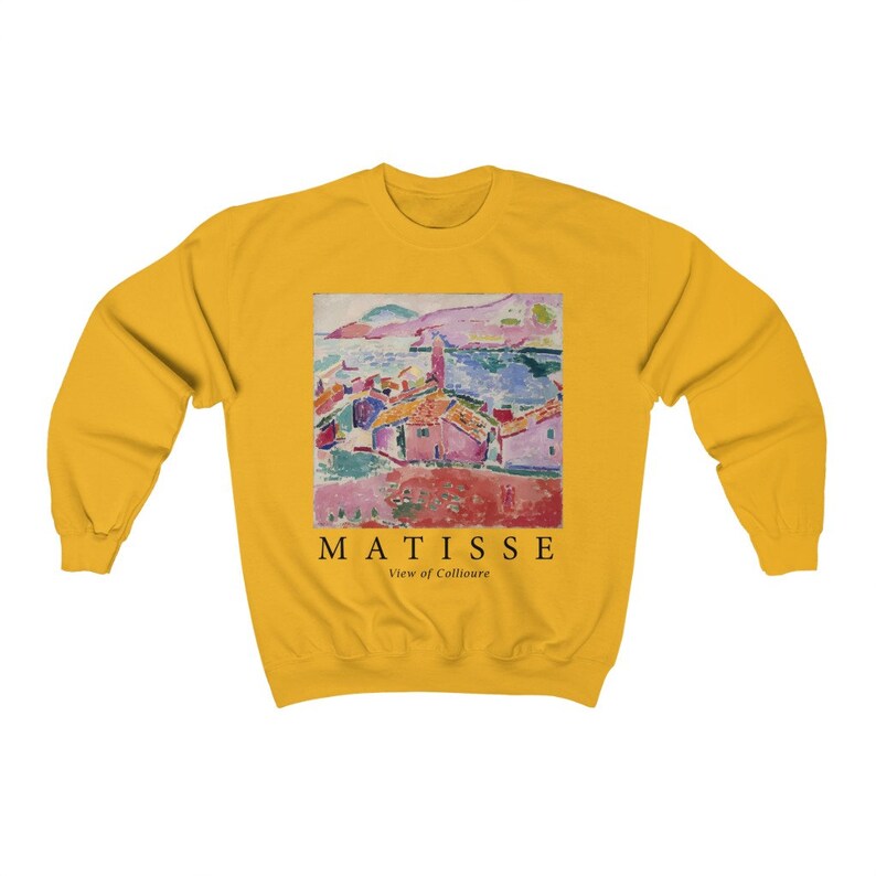 May include: Mustard yellow sweatshirt with a print of a Matisse painting depicting a coastal scene. The print includes the text "MATISSE View of Collioure". The sweatshirt has a crew neck and long sleeves.