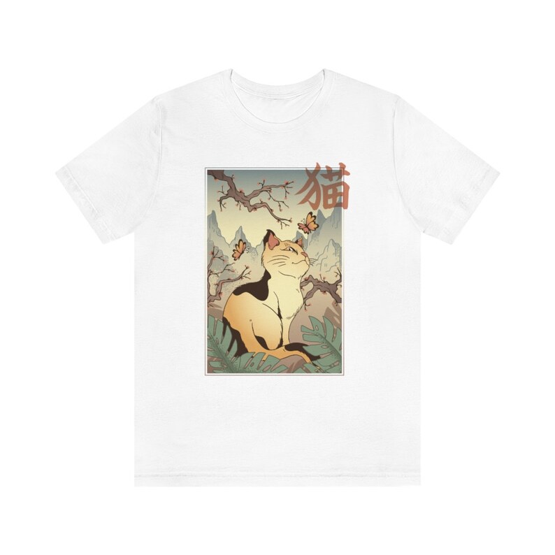 May include: White t-shirt with a Japanese-style illustration of a cat sitting in a forest with butterflies. The text "猫" is written in red on the shirt.