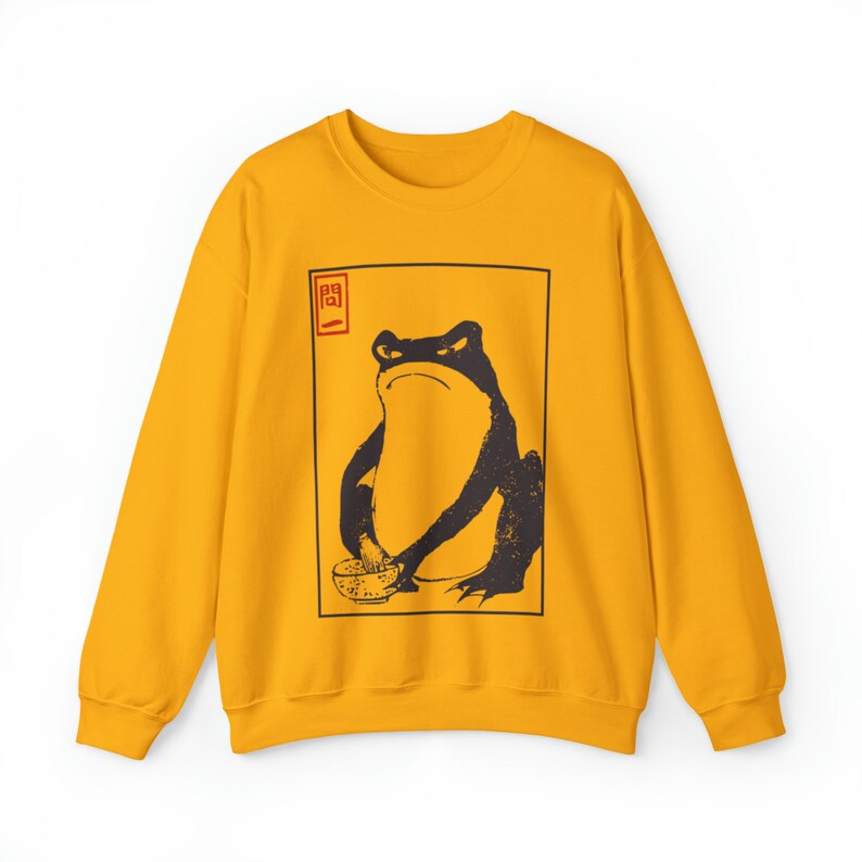 May include: A yellow sweatshirt with a black and white illustration of a frog holding a bowl. The frog is sitting in a square frame with the Japanese character "関" in red above it.