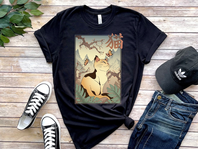 May include: Black t-shirt with a graphic of a cat sitting in a Japanese garden with butterflies. The text "猫" is written in Japanese on the graphic.