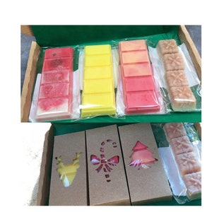 May include: A set of six wax melts in a cardboard box. The wax melts are in four different colors: red, yellow, orange, and pink. The box has cutouts in the shape of a reindeer, a candy cane, and a Christmas tree.