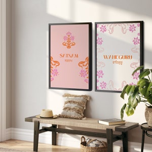 May include: Two framed prints with floral designs and text. The print on the left has a pink background with the text "SATNAM ਸਤਨਾਮ" in orange. The print on the right has a white background with the text "WAHEGURU ਵਾਹਿਗੁਰੂ" in orange.