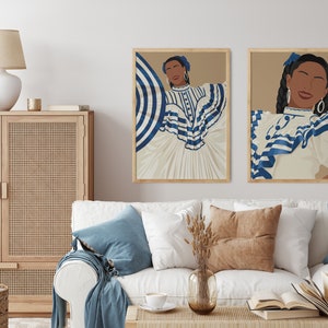 May include: Two framed illustrations of women wearing white and blue striped dresses. The women are smiling and have dark hair. The illustrations are set against a beige background.