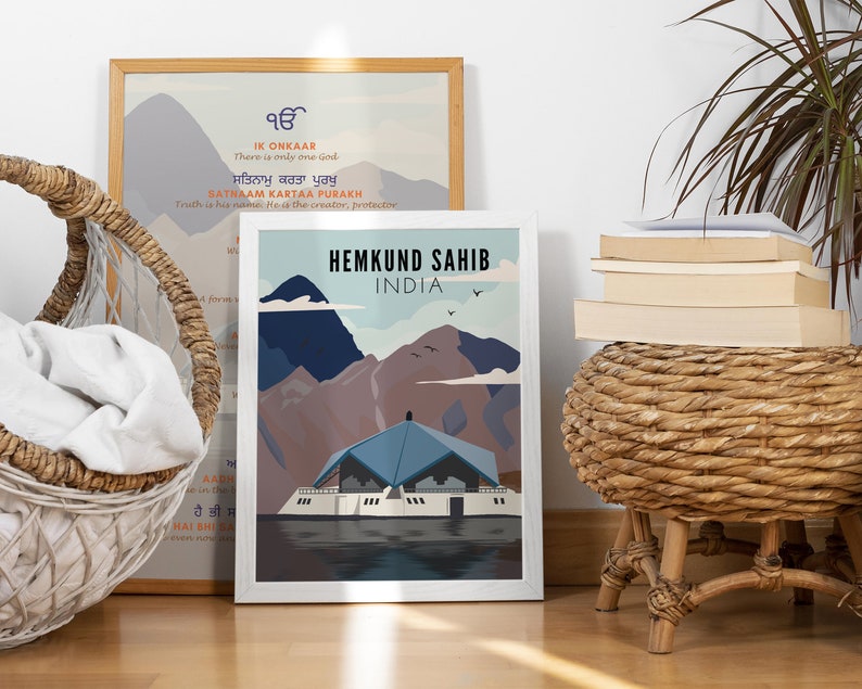 May include: A white framed print with a blue and brown illustration of a building with mountains in the background. The text "Hemkund Sahib India" is at the top of the print.
