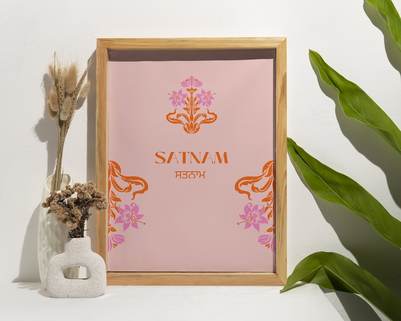May include: A framed print with a pink background and orange floral design. The text "SATNAM ਸਤਨਾਮ" is centered on the print.