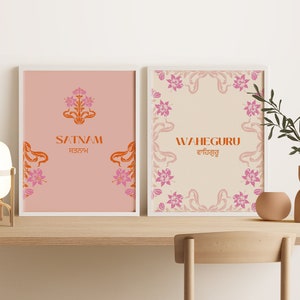 May include: Two framed prints with a peach and cream background. The prints feature floral designs and the words "Satnam" and "Waheguru" in orange and pink.