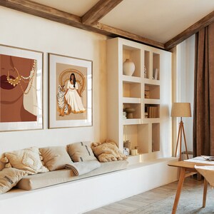 May include: Two framed illustrations of a woman in a white dress. The first illustration shows a close-up of the woman's face with gold jewelry. The second illustration shows the woman sitting on a throne with a tiger beside her. The illustrations are hanging on a white wall in a living room.