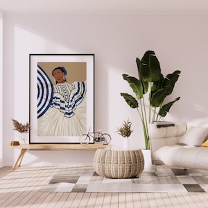 May include: A framed illustration of a woman wearing a white and blue striped dress with a blue and white striped umbrella. The illustration is hanging on a white wall above a wooden table with a potted plant and a bicycle. A white sofa with a yellow throw pillow is in the background.