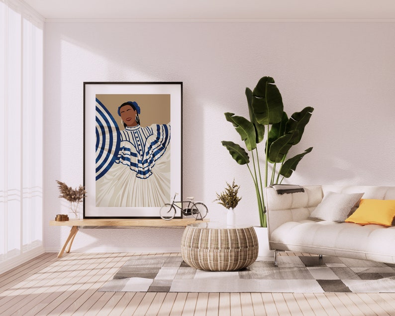 May include: A framed illustration of a woman wearing a white and blue striped dress with a blue and white striped umbrella. The illustration is hanging on a white wall above a wooden table with a potted plant and a bicycle. A white sofa with a yellow throw pillow is in the background.