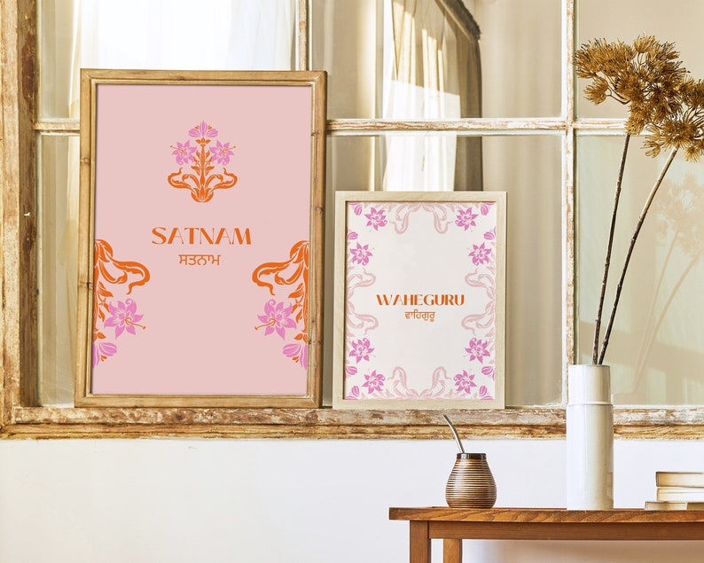 May include: Two framed prints with pink and orange floral designs. The top print says "SATNAM" in orange letters with the Punjabi word for "SATNAM" in smaller orange letters below. The bottom print says "WAHEGURU" in orange letters with the Punjabi word for "WAHEGURU" in smaller orange letters below.