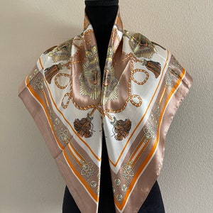 May include: A brown silk scarf with a white center featuring a nautical design with anchors, ropes, and tassels. The scarf has a gold and orange trim.