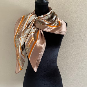 May include: A brown silk scarf with a white and orange geometric pattern. The scarf features a repeating design of rope and knots.