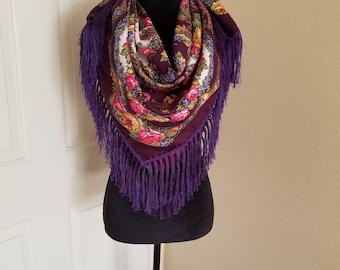 Può includere: Una sciarpa viola con motivo paisley e design floreale con frange viola.