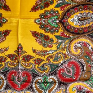 Pu&ograve; includere: Una sciarpa di seta gialla con un motivo paisley dettagliato nei toni del rosso, verde, marrone e rosa. La sciarpa ha una finitura lucida e un design classico, adatta a varie occasioni.