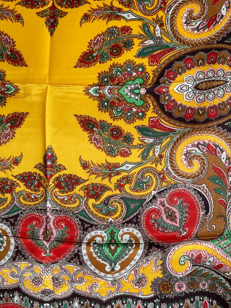 Pu&ograve; includere: Una sciarpa di seta gialla con un motivo paisley dettagliato nei toni del rosso, verde, marrone e rosa. La sciarpa ha una finitura lucida e un design classico, adatta a varie occasioni.