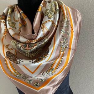 May include: A brown silk scarf with a white and orange pattern of nautical rope, anchors, and crests.