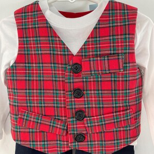 May include: A red and green plaid vest with four black buttons, a white long-sleeved shirt, and black pants.