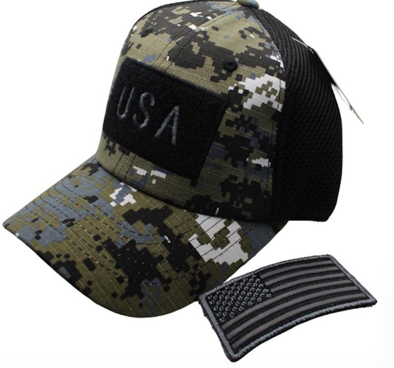 May include: A camouflage baseball cap with a black mesh back and a black patch that says "USA". The cap comes with a black and gray American flag patch.