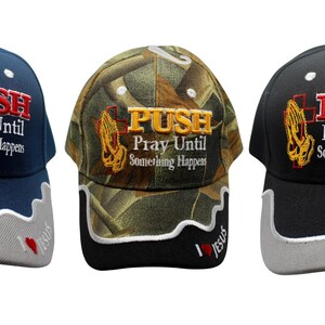 May include: Three baseball caps with the text "PUSH Pray Until Something Happens." One is navy blue, one is camouflage, and one is black. Each cap has a white and gray brim with "I ❤️ JESUS" text.