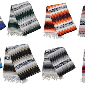 Puede incluir: Una colección de ocho mantas tejidas plegadas con diversas combinaciones de colores, incluyendo azul, verde, naranja, rosa, azul claro, beige, gris y rojo. Cada manta muestra un patrón geométrico de diamantes repetitivo y flecos blancos.