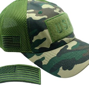 May include: A green camouflage baseball cap with a mesh back panel. The cap has a green velcro patch with the text "U.S.A." embroidered on it. The cap also has a small green and black American flag patch on the side. A separate green and black American flag patch is also included.