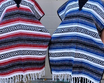 May include: Two colorful Mexican ponchos with fringe. One poncho is red, white, and black, and the other is blue, white, and black.